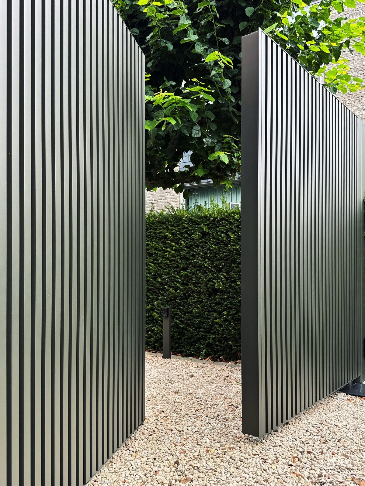 Open poortvleugels in olijfgroen met doorkijk naar de oprit en de tuin
